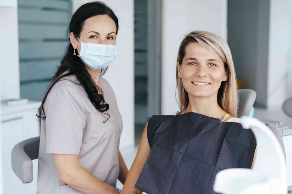 Smiling patient with dental professional in treatment room before a denture consultation.